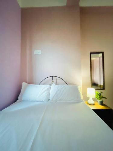 a bed with white sheets and a mirror and a lamp at Renade Leisure Stay in Agartala
