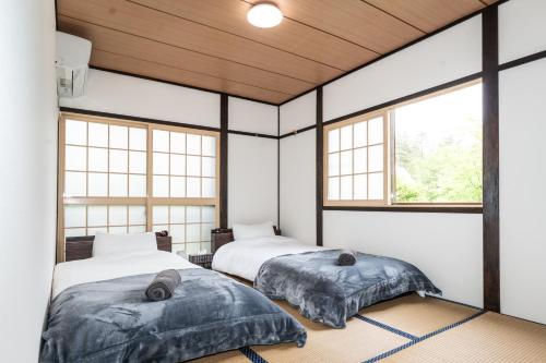 two beds in a room with windows at Ringo Cottage in Hakuba