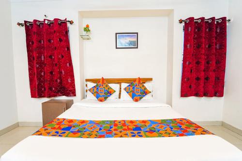 a bedroom with a bed with red curtains at FabExpress Mann Pasand Inn in Bangalore