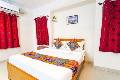 a bedroom with a bed and red curtains at FabExpress Mann Pasand Inn in Bangalore