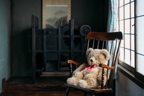 a teddy bear sitting on a wooden chair at CASA DE YOSHi 一棟貸し in Yamagata