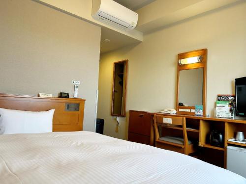 a hotel room with a bed and a desk and a mirror at Hotel Route-Inn Chiryu -Kokudou 1 Gou- in Chiryu