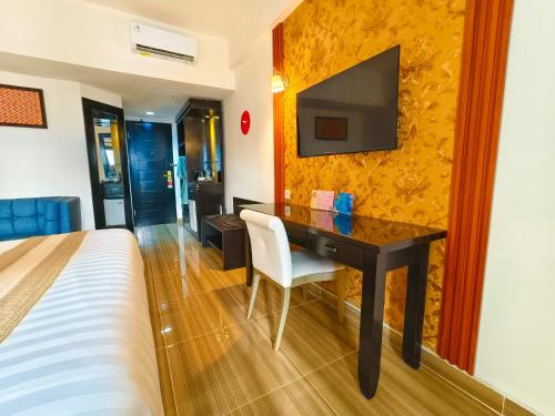 a bedroom with a desk with a television on a wall at The Tandibayang Hotel & Villas in Badung