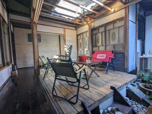 a room with a table and chairs on a deck at まろや四季 in Ōzu