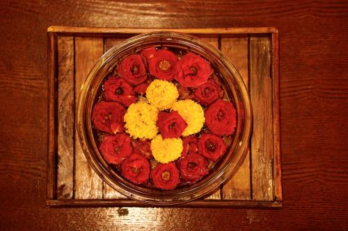 a glass bowl filled with red and yellow flowers at The Windchimes Retreat Coorg in Virajpet