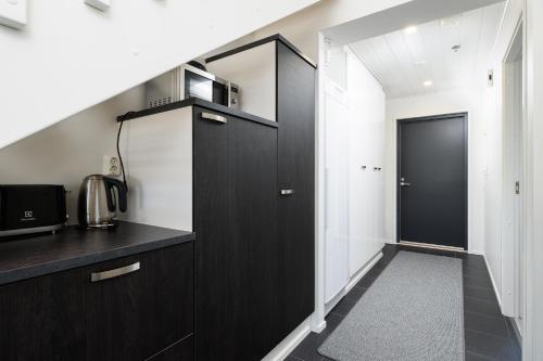 a kitchen with black cabinets and a black door at Hilmantori Apartments by Hiekka Booking in Kalajoki