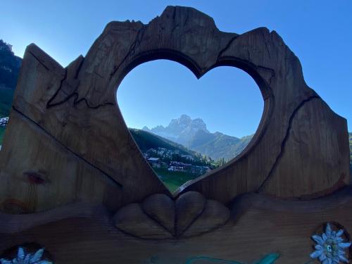 serce wyrzeźbione w kawałek drewna z górami w tle w obiekcie Garní Ladinia w mieście Pescul