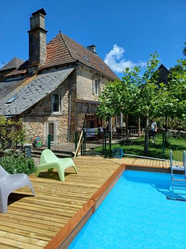 une terrasse en bois avec une piscine et une maison dans l'établissement Maison Village Hautefage, à Hautefage