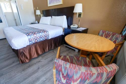 ペイソンにあるRim Country Inn Paysonのベッド、テーブル、椅子が備わるホテルルームです。
