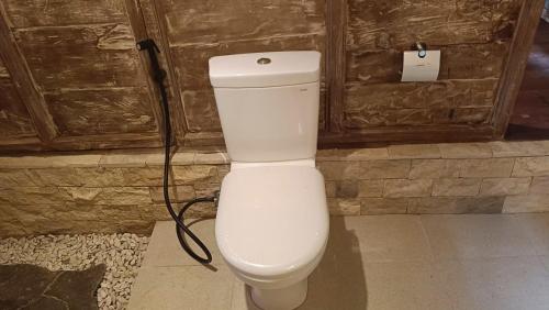 a white toilet in a room with a wall at D'Ume Bendoel Homestay in Jatiluwih