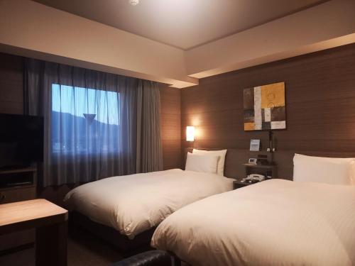 Chuoにあるホテルルートイン山梨中央のベッド2台と窓が備わるホテルルームです。