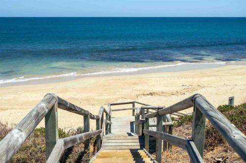 a wooden staircase leading to a beach with the ocean at Relaxing Getaway Beachfront Access Multi Family Pets Mandurah in Mandurah