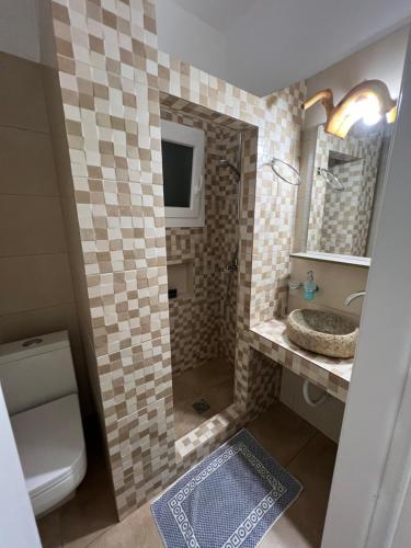 a bathroom with a sink and a toilet and a mirror at Alexandra’s studios in Iraklia