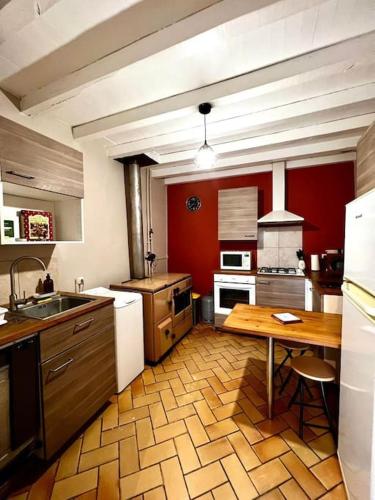 Il comprend une cuisine avec une table en bois et des murs rouges. dans l'établissement Gîte de Pierrot, à Vicq