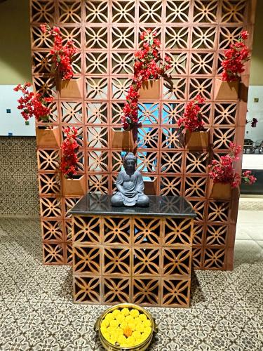 a statue in front of a wall with flowers at The Windchimes Retreat Coorg in Virajpet