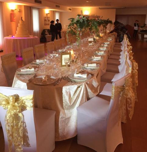 a long long table with white tables and chairs at Hotel In Sylvis in Sesto al Reghena