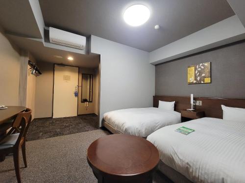 a hotel room with two beds and a table at HOTEL ROUTE-INN Ota Minami -Kokudo 407 Gou- in Ota