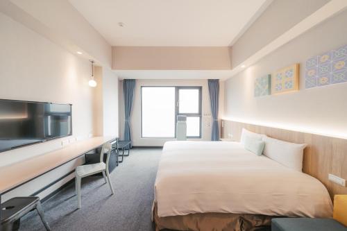 a hotel room with a bed and a desk and a tv at Hotel Liyaou in Chiayi City