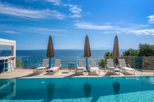 a pool with chairs and a table and umbrellas at Pelagos Blue Zante in Vasilikos