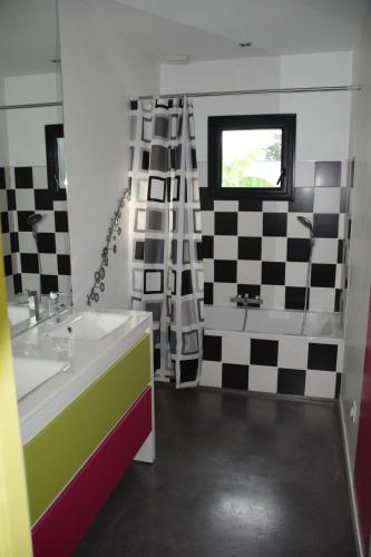 La salle de bains est pourvue d'un lavabo et d'un mur en damier. dans l'établissement Villa plage piscine chauffée, à La Bernerie-en-Retz