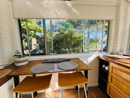 a kitchen with a table and two chairs and a window at Brunswick Riverfront Apartment - Absolute Riverfront in Brunswick Heads