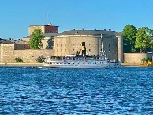 a boat on the water in front of a building at Vaxholm Skarpö archipelago island living with car access in Vaxholm