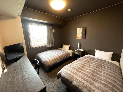 a hotel room with two beds and a window at Hotel Route-Inn Gifukencho Minami in Gifu