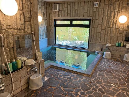 a large bathroom with a swimming pool in it at Hotel Route-Inn Gifukencho Minami in Gifu