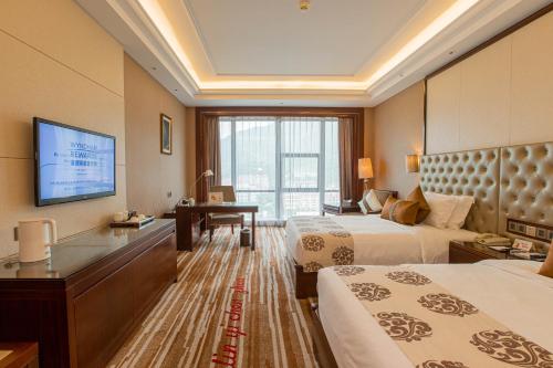 a hotel room with two beds and a flat screen tv at Wyndham Grand Plaza Royale Chenzhou in Chenzhou