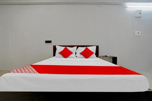 a bedroom with a large bed with red pillows at Hotel Welcome, VIP Road Vesu in Surat