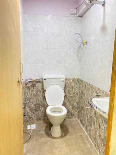 a bathroom with a toilet and a sink at Hotel Welcome, VIP Road Vesu in Surat