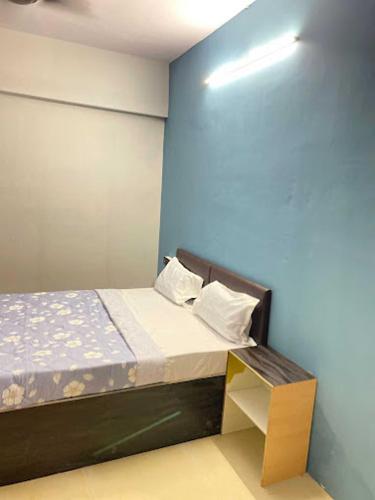 a bedroom with a bed and a blue wall at Hotel Welcome, VIP Road Vesu in Surat