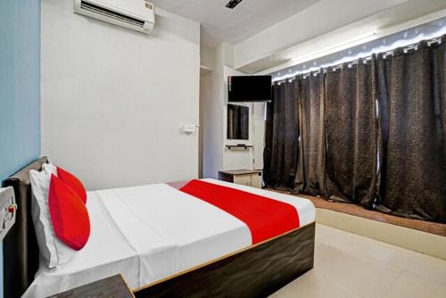 a bedroom with a red and white bed and a window at Hotel Welcome, VIP Road Vesu in Surat