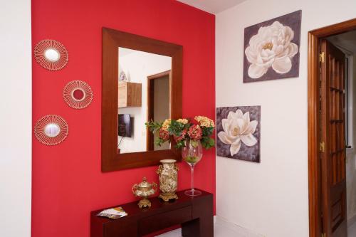 a red room with a mirror and a vase of flowers on a table at Antoxos Sacra Home I in Chantada
