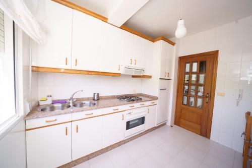 a kitchen with white cabinets and a sink at Antoxos Sacra Home I in Chantada
