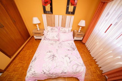 a bedroom with a bed with a pink and white comforter at Antoxos Sacra Home I in Chantada
