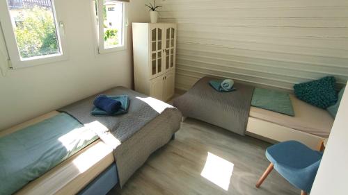 a small bedroom with two beds and a chair at Madarász 7 Deluxe Vendégház in Balatonalmádi