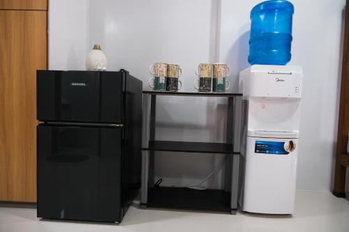 a black refrigerator next to a table with a blue bottle on it at Hangout Haven Siargao Homestay in Dapa