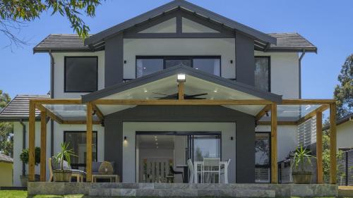 a house with a conservatory with chairs in front of it at Tallowwood in Pokolbin