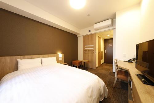 a hotel room with a bed and a television at Dormy Inn Maebashi in Maebashi