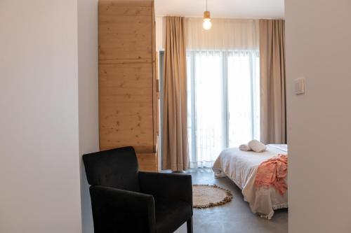 a bedroom with a bed and a chair and a window at Li Mango in Tigaki