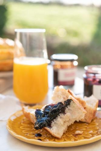 einen Teller mit einem Stück Brot und einem Glas Orangensaft in der Unterkunft Domaine Beaumont in Distré