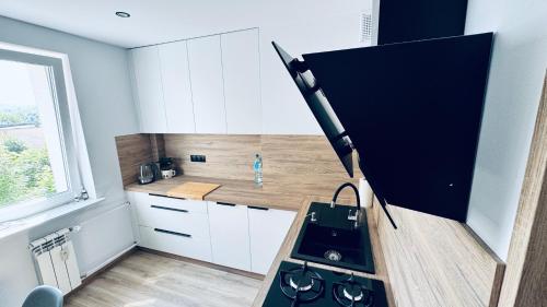 a small kitchen with a black stove and white cabinets at Apartament Daszyńskiego in Sanok