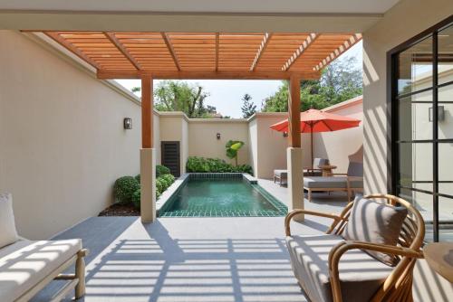 un patio al aire libre con piscina y sombrilla en Anantasila Beach Resort Hua Hin, en Hua Hin