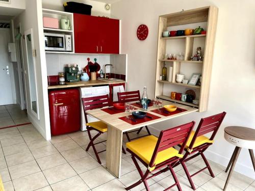 une cuisine avec des armoires rouges et une table et des chaises dans l'établissement Studio de Saint-Laurent 200m de la plage, à Saint-Laurent-du-Var