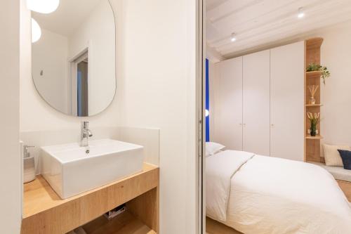 - une salle de bains blanche pourvue d'un lavabo et d'un lit dans l'établissement Geranimus : Heart of Paris Montorgeuil, à Paris