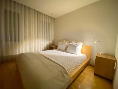 a bedroom with a bed with white sheets and a window at Apartments Atlantis by UR in Vila Nova de Gaia