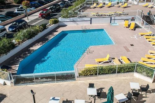 - une vue sur la piscine avec des chaises et un parking dans l'établissement Duplex Hendaye-plage, à Hendaye