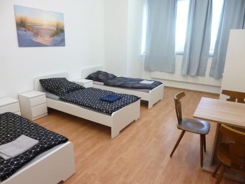 3 lits dans une chambre avec une table et une chaise dans l'établissement Nice Apartment in Vöhringen, à Vöhringen