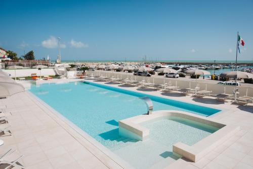 a large swimming pool with chairs and umbrellas at Hotel Scogliera in Numana